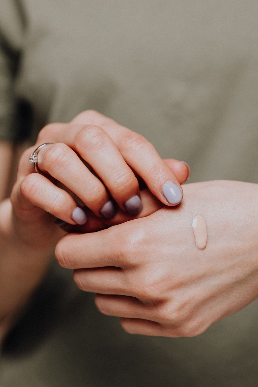 Hands demonstrating a product — skincare foundation application close-up
